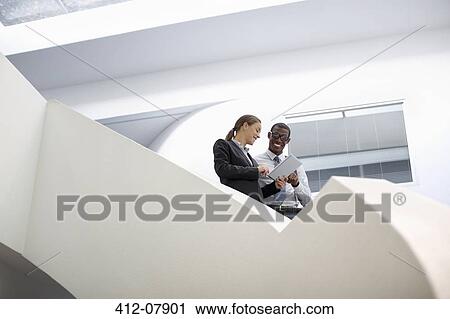 Businessman and businesswoman using digital tablet on modern staircase View Large Photo Image Stock Image - Businessman and businesswoman using digital tablet on modern staircase. Fotosearch