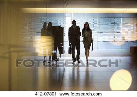 Businessman and businesswoman walking in lobby View Large Photo Image Stock Image - Businessman and businesswoman walking in lobby. Fotosearch