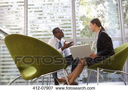 Businessman and businesswoman with laptop talking in lobby View Large Photo Image Stock Photo - Businessman and businesswoman with laptop talking in lobby. Fotosearch