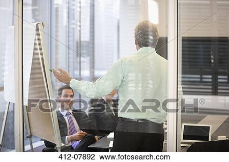 Businessman at flipchart in meeting View Large Photo Image Stock Image - Businessman at flipchart in meeting. Fotosearch