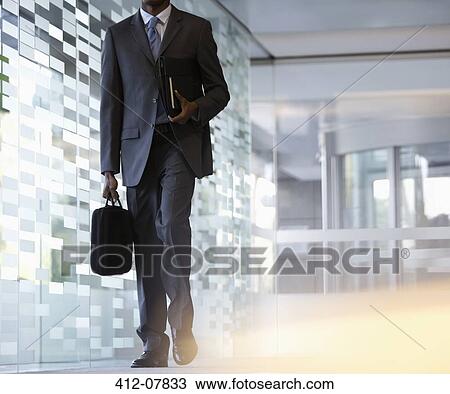 Businessman carrying briefcase in lobby View Large Photo Image Stock Image - Businessman carrying briefcase in lobby. Fotosearch