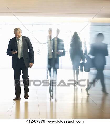 Businessman checking cell phone in lobby View Large Photo Image Stock Photograph - Businessman checking cell phone in lobby. Fotosearch