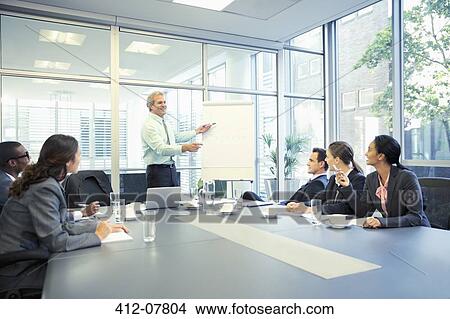 Businessman leading meeting at flipchart in conference room View Large Photo Image Picture - Businessman leading meeting at flipchart in conference room. Fotosearch