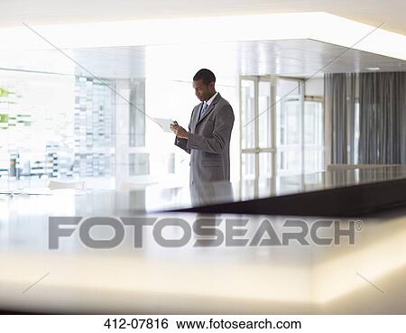 Stock Photograph - Businessman using digital tablet in lobby. Fotosearch