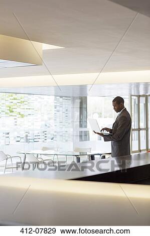 Businessman using laptop in lobby View Large Photo Image Stock Photo - Businessman using laptop in lobby. Fotosearch