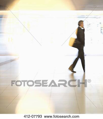 Stock Image - Businessman walking in lobby. Fotosearch