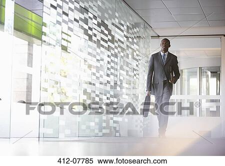 Stock Photography - Businessman with briefcase walking in lobby. Fotosearch