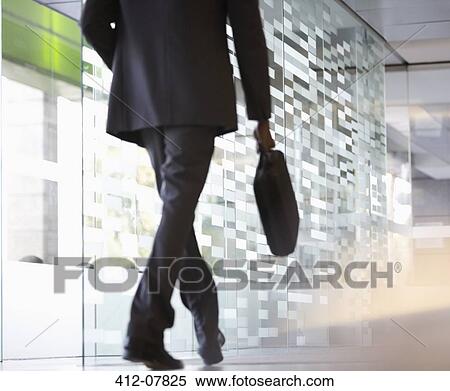 Stock Photography - Businessman with briefcase walking in lobby. Fotosearch