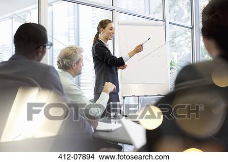 Businesswoman at flipchart leading meeting in conference room View Large Photo Image Picture - Businesswoman at flipchart leading meeting in conference room. Fotosearch