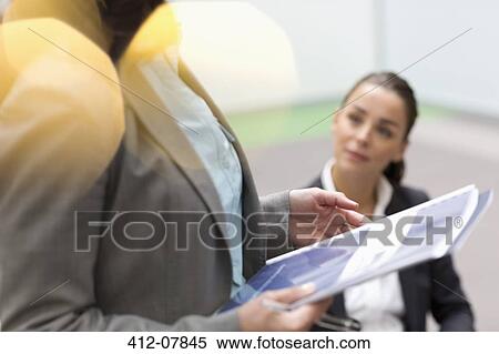 Stock Photography - Businesswoman holding paperwork in meeting. Fotosearch