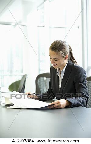 Businesswoman reading paperwork in conference room View Large Photo Image Picture - Businesswoman reading paperwork in conference room. Fotosearch