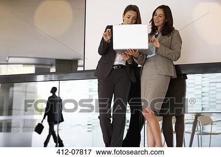 Businesswomen using laptop in lobby View Large Photo Image Stock Photo - Businesswomen using laptop in lobby. Fotosearch