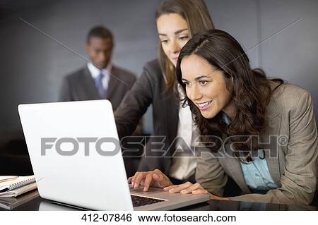 Businesswomen using laptop in office View Large Photo Image Stock Photograph - Businesswomen using laptop in office. Fotosearch