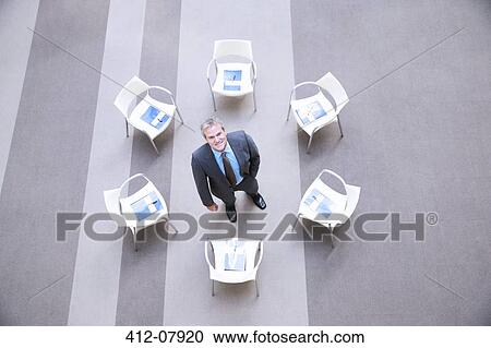 High angle portrait of smiling businessman at center of chairs in circle View Large Photo Image Stock Image - High angle portrait of smiling businessman at center of chairs in circle. Fotosearch