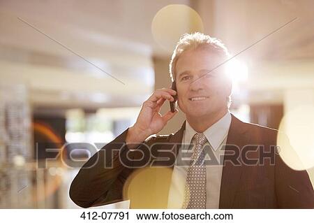 Stock Image - Portrait of confident businessman talking on cell phone. Fotosearch