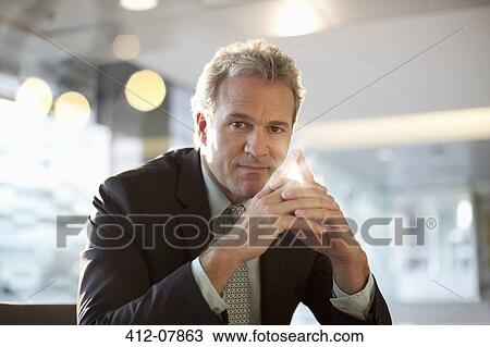 Portrait of confident businessman with hands clasped View Large Photo Image Stock Image - Portrait of confident businessman with hands clasped. Fotosearch