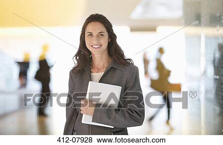 Portrait of smiling businesswoman holding digital tablet in lobby View Large Photo Image Stock Photo - Portrait of smiling businesswoman holding digital tablet in lobby. Fotosearch