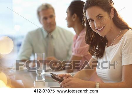 Portrait of smiling businesswoman with cell phone in meeting View Large Photo Image Stock Photography - Portrait of smiling businesswoman with cell phone in meeting. Fotosearch
