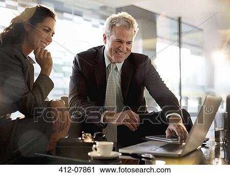 Smiling businessman and businesswoman using laptop in lobby View Large Photo Image Stock Image - Smiling businessman and businesswoman using laptop in lobby. Fotosearch