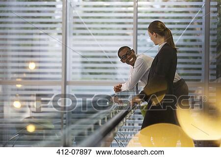 Stock Photo - Smiling businessman and businesswoman talking in office. Fotosearch