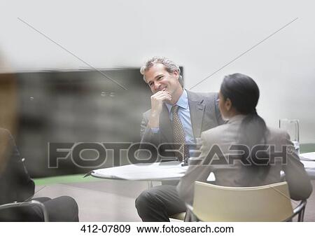 Smiling businessman in meeting View Large Photo Image Stock Photo - Smiling businessman in meeting. Fotosearch