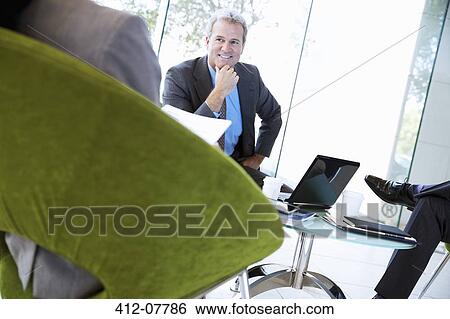 Stock Photograph - Smiling businessman in meeting. Fotosearch