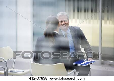 Smiling businessman talking to businesswoman View Large Photo Image Stock Photo - Smiling businessman talking to businesswoman. Fotosearch