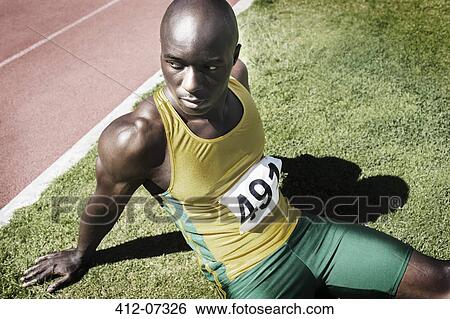 Athlete resting in grass next to running track View Large Photo Image Stock Photograph - Athlete resting in grass next to running track. Fotosearch