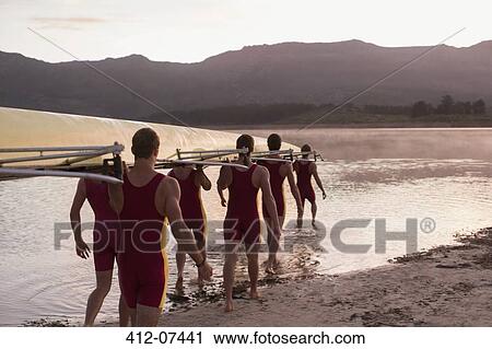 Rowing team carrying scull into lake at dawn View Large Photo Image Stock Image - Rowing team carrying scull into lake at dawn. Fotosearch