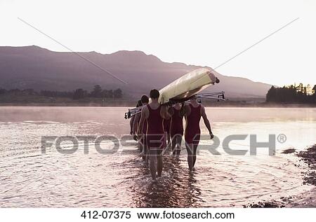 Stock Photography - Rowing team carrying scull into lake. Fotosearch