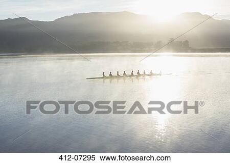 Rowing team rowing boat on still lake View Large Photo Image Stock Photography - Rowing team rowing boat on still lake. Fotosearch