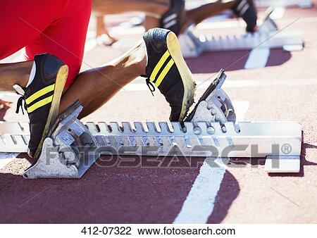 Stock Image - Runner's feet in starting blocks on track. Fotosearch