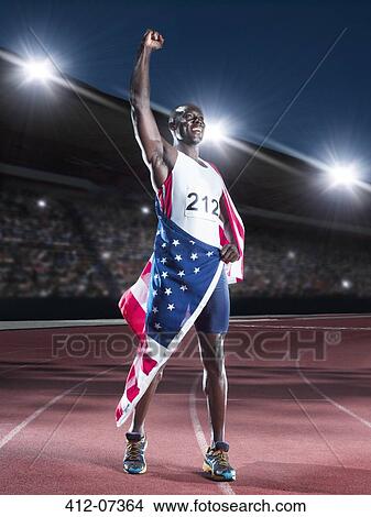 Picture - Track and field athlete wrapped in American flag on track. Fotosearch