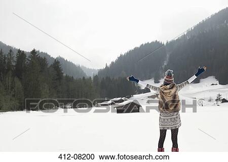 Carefree woman with arms outstretched in snowy field View Large Photo Image Stock Image - Carefree woman with arms outstretched in snowy field. Fotosearch