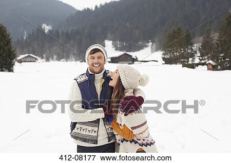 Stock Photo - Couple hugging and laughing in snowy field. Fotosearch