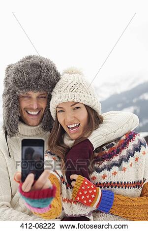 Stock Image - Enthusiastic couple taking self-portrait with camera phone. Fotosearch