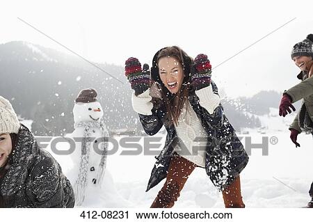 Enthusiastic friends enjoying snowball fight in field View Large Photo Image Stock Image - Enthusiastic friends enjoying snowball fight in field. Fotosearch