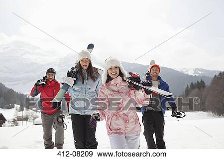 Stock Photo - Enthusiastic friends with skis in snowy field. Fotosearch