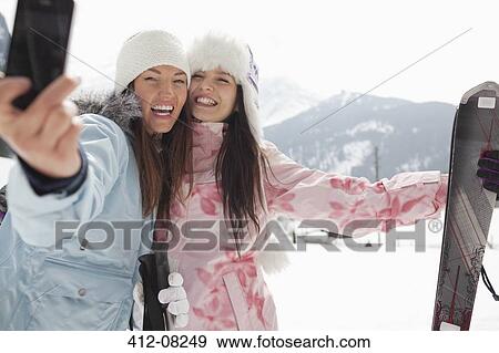 Enthusiastic women with skis taking self-portrait with camera phone in field View Large Photo Image Stock Photo - Enthusiastic women with skis taking self-portrait with camera phone in field. Fotosearch