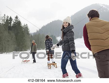 Friends pulling sleds in snowy field View Large Photo Image Picture - Friends pulling sleds in snowy field. Fotosearch