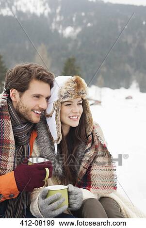 Stock Photo - Happy couple drinking coffee in snowy field. Fotosearch