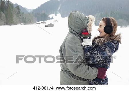Happy couple hugging in snowy field View Large Photo Image Picture - Happy couple hugging in snowy field. Fotosearch