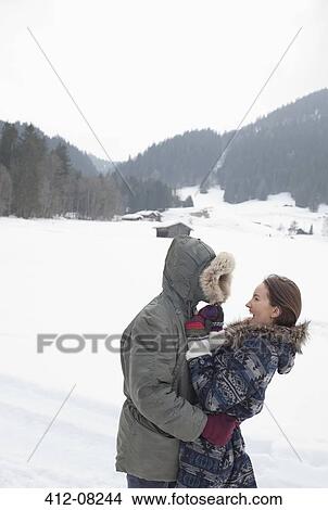 Happy couple hugging in snowy field View Large Photo Image Picture - Happy couple hugging in snowy field. Fotosearch