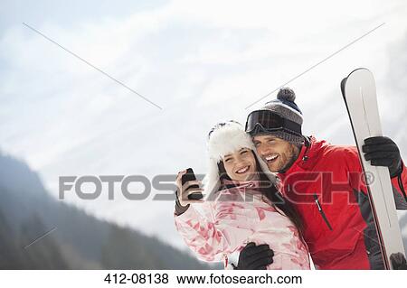 Happy couple with skis taking self-portrait with camera phone View Large Photo Image Stock Photo - Happy couple with skis taking self-portrait with camera phone. Fotosearch