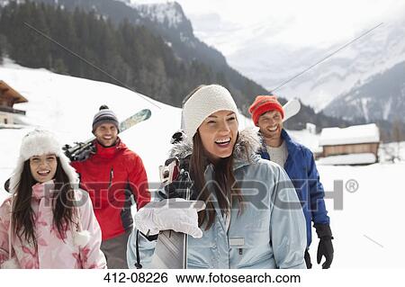 Happy friends carrying skis in snowy field View Large Photo Image Stock Photograph - Happy friends carrying skis in snowy field. Fotosearch