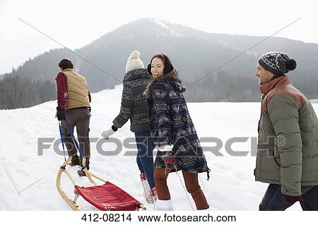 Picture - Happy friends pulling sleds in snowy field. Fotosearch