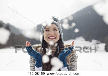 Stock Photo - Happy woman enjoying falling snow in field. Fotosearch
