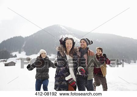 Stock Image - Playful friends enjoying snowball fight in field. Fotosearch