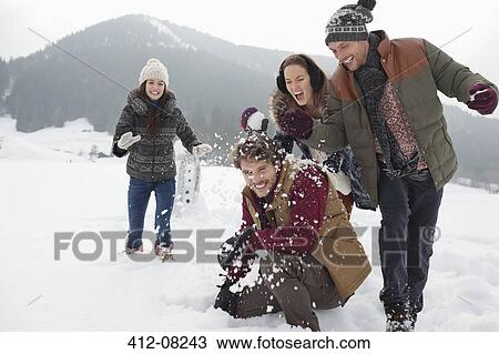 Stock Image - Playful friends enjoying snowball fight in field. Fotosearch