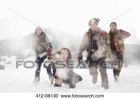 Stock Image - Portrait of friends playing in snowy field. Fotosearch